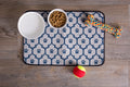 Ceramic Pet Bowl Set for Food and Water placed on a paw-print mat with a toy and ball.